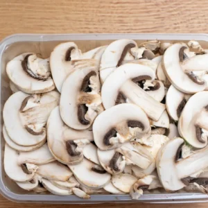 Sliced button mushrooms in plastic container