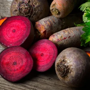 Sliced and whole red beets on wooden surface