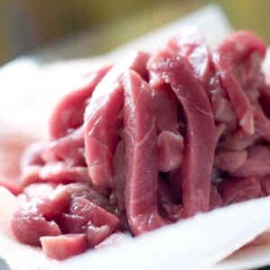 Raw thinly sliced red meat on plate