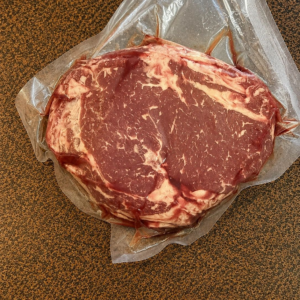 Packaged raw steak on brown surface