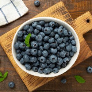 Bowl of fresh blueberries on wooden board